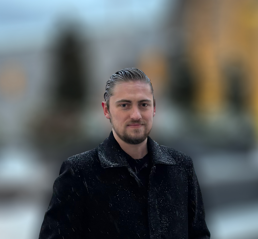 Bradley McMahan wearing a dark coat against a blurred outdoor background.